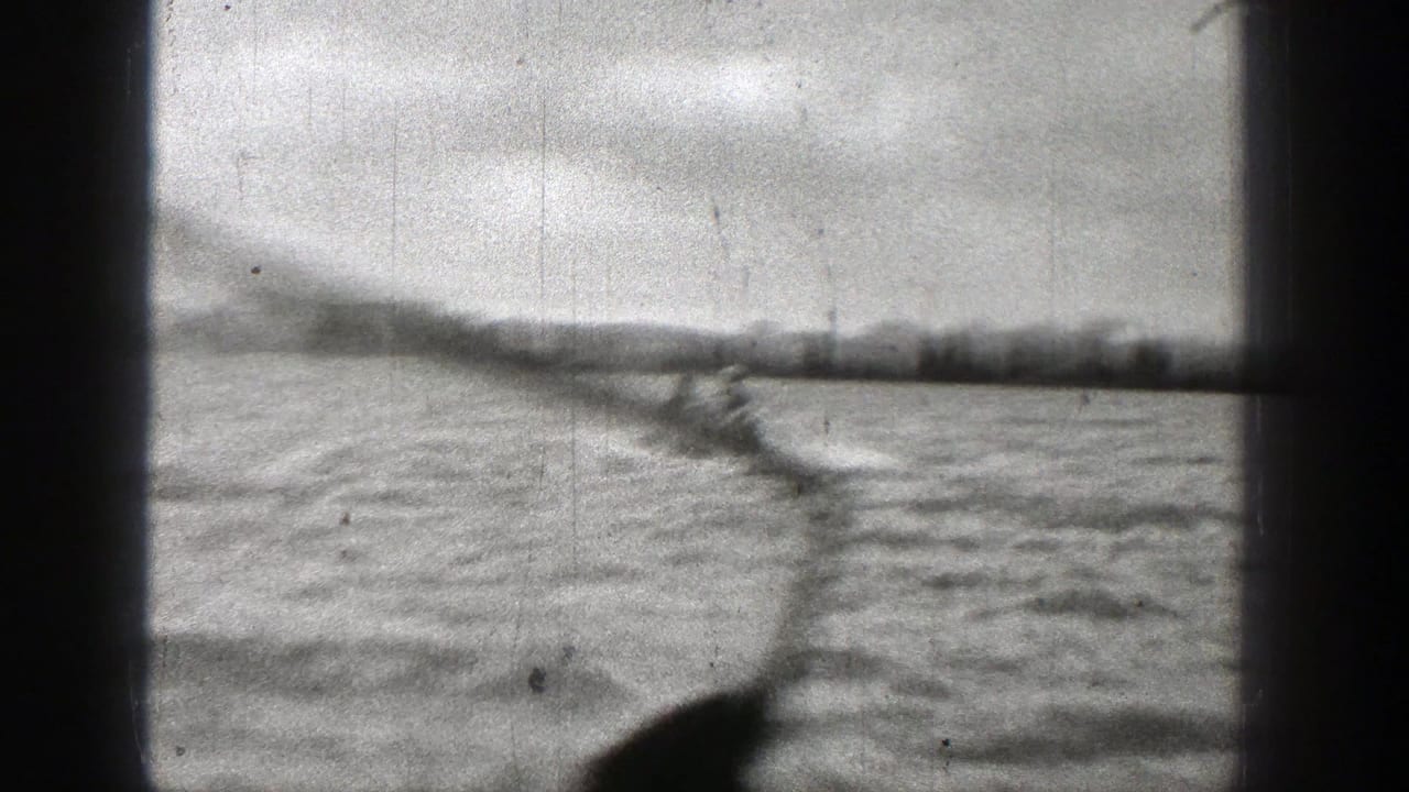 1938 Washington home-movie frame with the speedboat partly low in frame and a long wake trailing across the water.