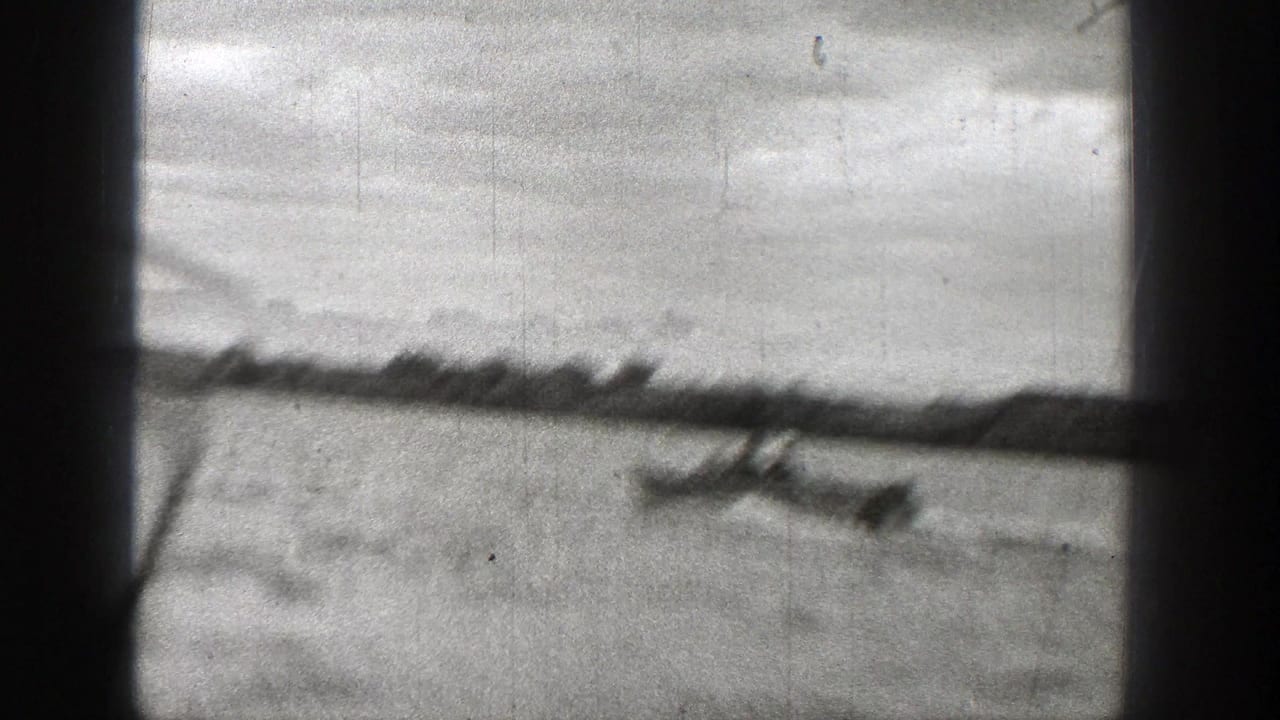 A blurred 1938 Washington 8mm frame shows the motorboat moving across open water below a low distant shoreline.