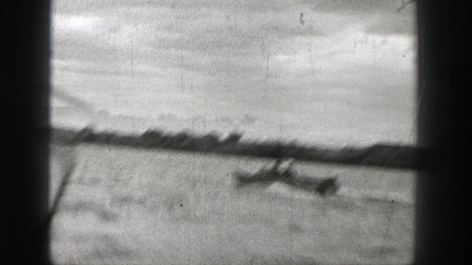 A blurred 1938 Washington 8mm frame shows the motorboat moving across open water below a low distant shoreline.