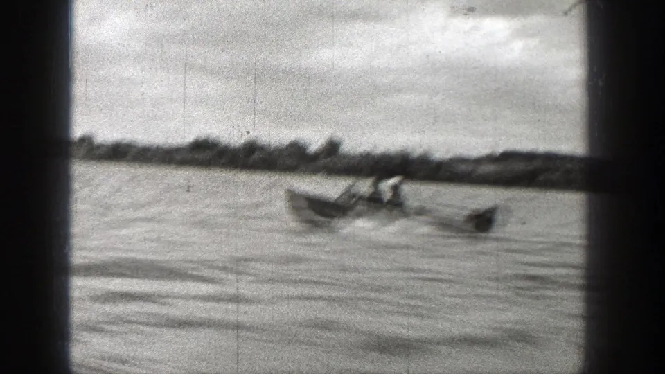 Small boat with several people rides across the river in 1938 Washington home-movie footage, with wake trailing behind.