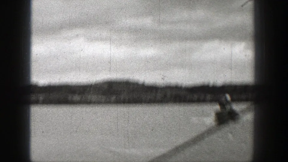 1938 Washington lake footage with a small speedboat passing low in frame beneath dark cabin or window bars.