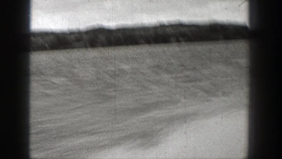 1938 Washington home-movie frame showing open water, low distant land, cloudy sky, and dark film gate edges.