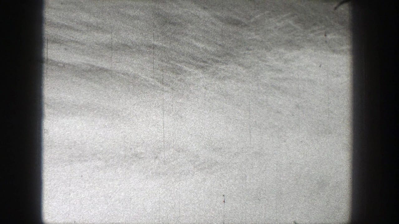 Black-and-white 1938 Washington home-movie frame showing water and cloudy sky through dark vertical window or porthole framing.