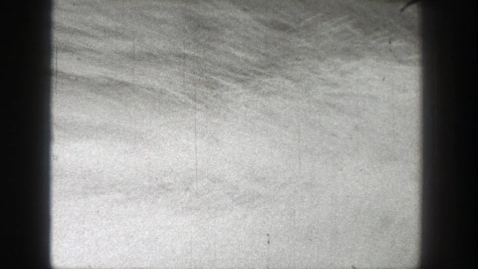 Black-and-white 1938 Washington home-movie frame showing water and cloudy sky through dark vertical window or porthole framing.