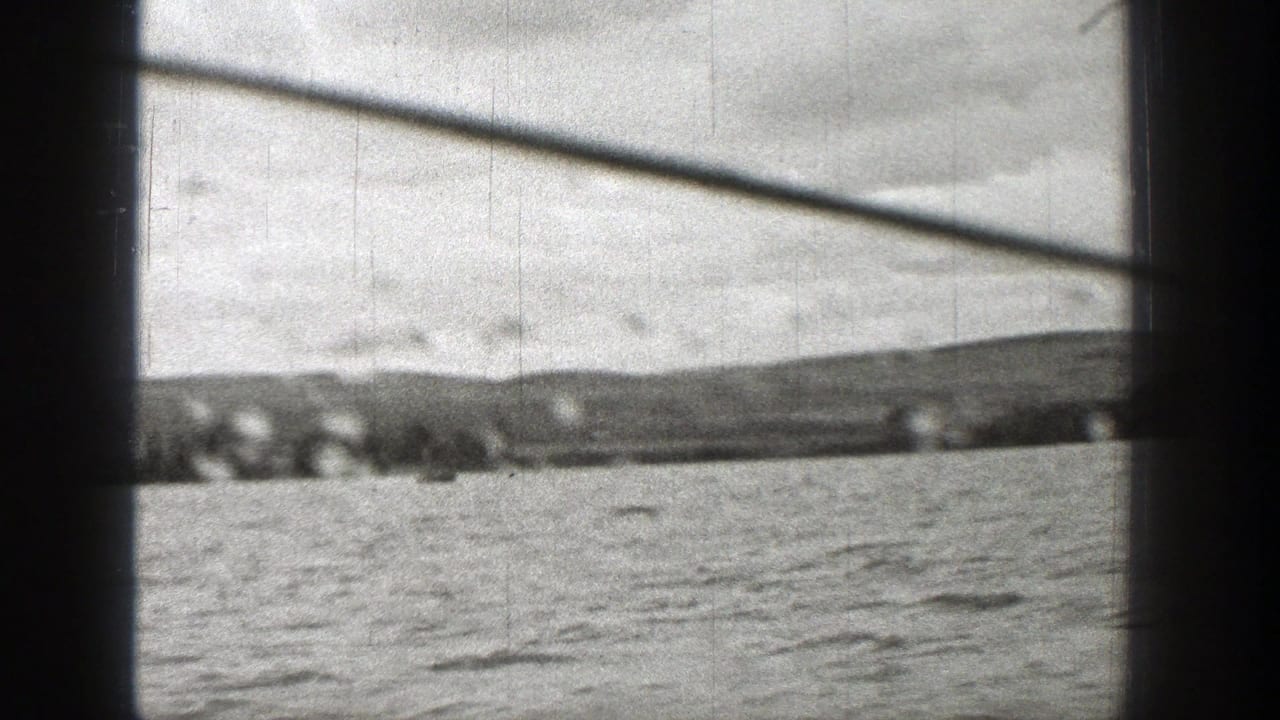 Distant shoreline and water framed by dark bars and a diagonal structure.