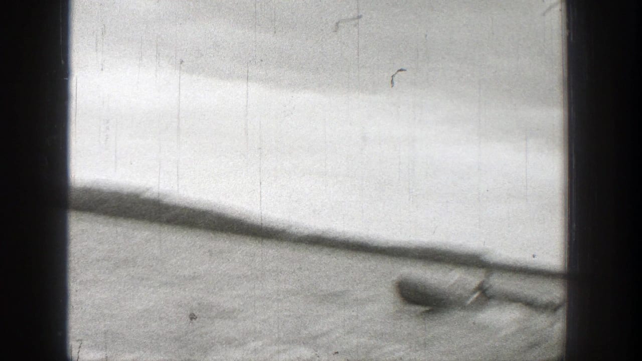 1938 Washington 8mm frame showing a small boat on open water with a low shoreline in the distance.