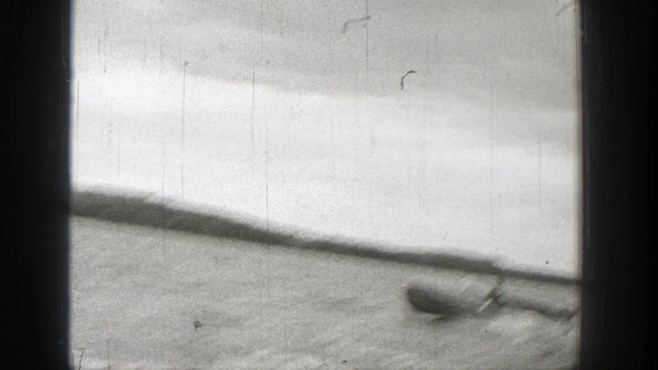 1938 Washington 8mm frame showing a small boat on open water with a low shoreline in the distance.