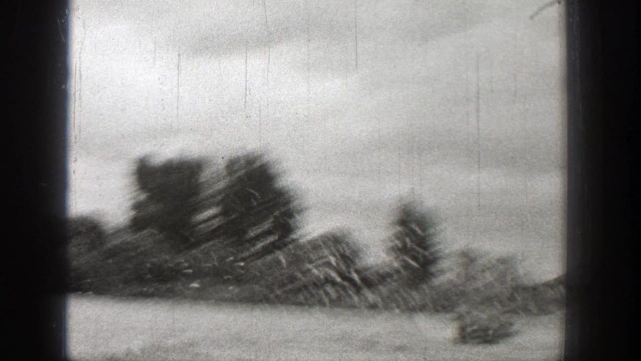 1938 Washington 8mm frame with blurred water, distant shoreline trees, cloudy sky, and visible black frame borders.