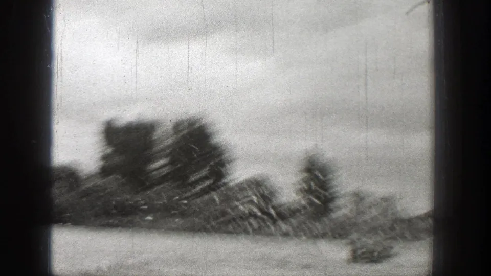 1938 Washington 8mm frame with blurred water, distant shoreline trees, cloudy sky, and visible black frame borders.