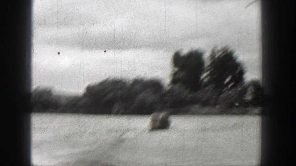 1938 Washington 8mm frame showing a blurred small object on water, dark tree line, cloudy sky, and visible film wear.
