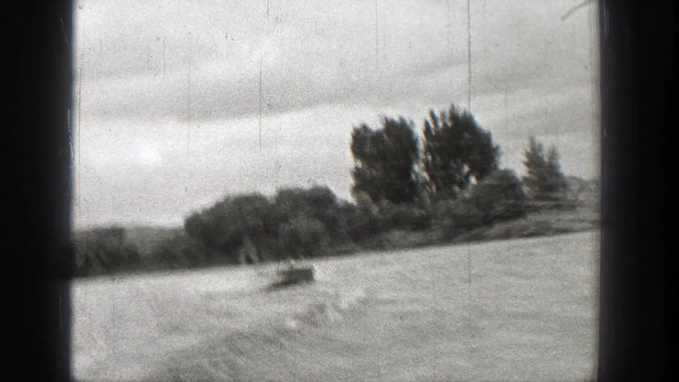 1938 Washington 8mm frame showing rough water, distant trees, low hills, and an overcast sky from a shaky moving viewpoint.