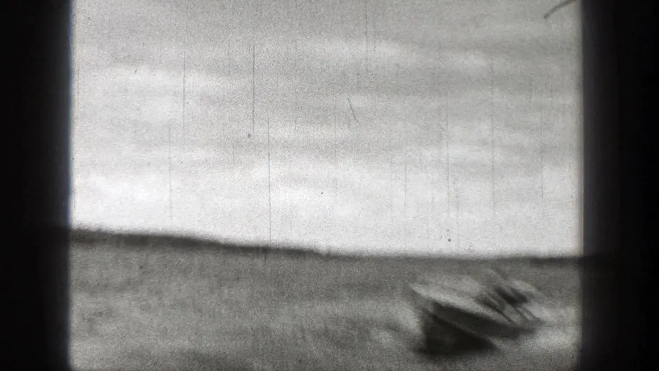 1938 Washington 8mm frame showing a motorboat moving across a lake, with a hilly shoreline and dark film-frame edges visible.