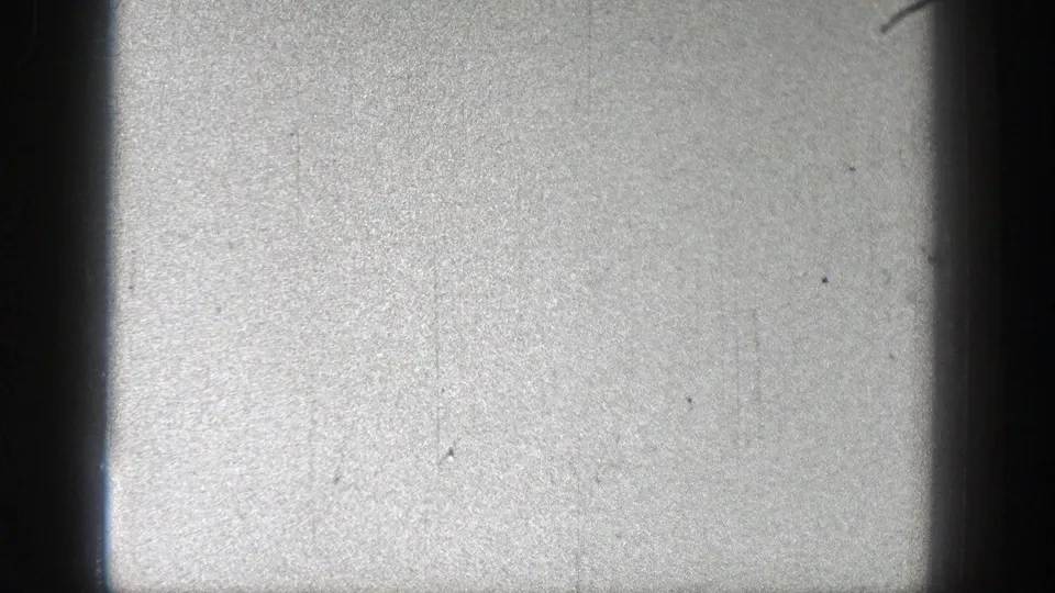 Pale, lightly exposed 8mm frame from the Washington 1938 clip, showing film grain, scratches, and dark gate edges with no clear subject visible.