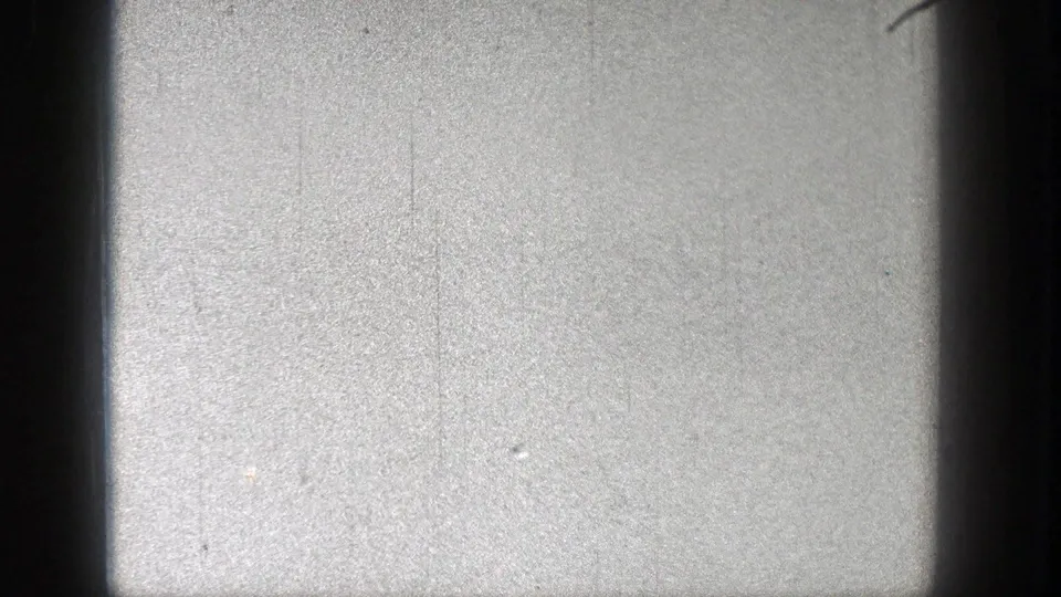Washington 1938 home-movie frame with a pale sky-like field, minor specks, scratches, and dark film borders but no distinct subject.