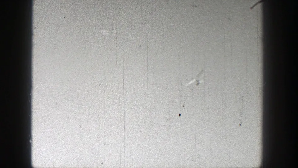A small white model airplane appears high in a bright sky in 1938 Washington home-movie footage, with visible 8mm grain and dust.