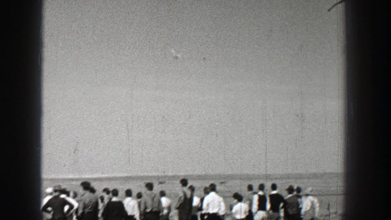 Spectators lined along a field edge under a wide sky.