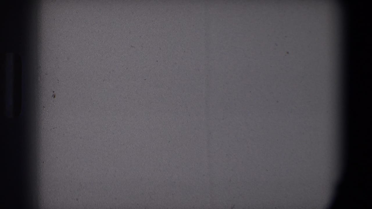Obscured 8mm frame from the Saint Paul 1971 Christmas clip, with gray exposure area and only a small portion of the tree visible.