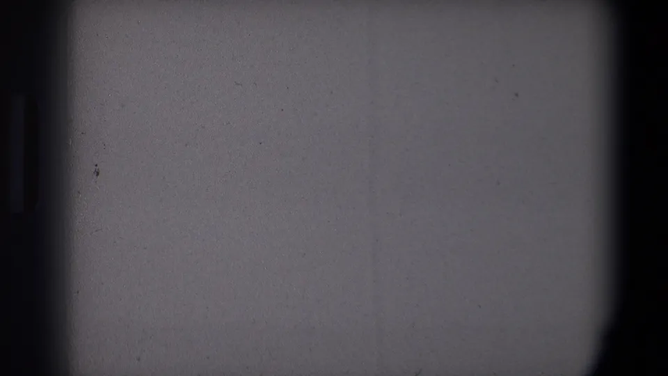 Obscured 8mm frame from the Saint Paul 1971 Christmas clip, with gray exposure area and only a small portion of the tree visible.