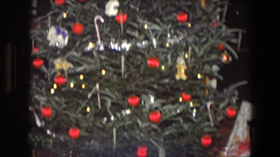 Close 1971 Saint Paul home-movie view of a Christmas tree with red ball ornaments, lights, and small hanging decorations.