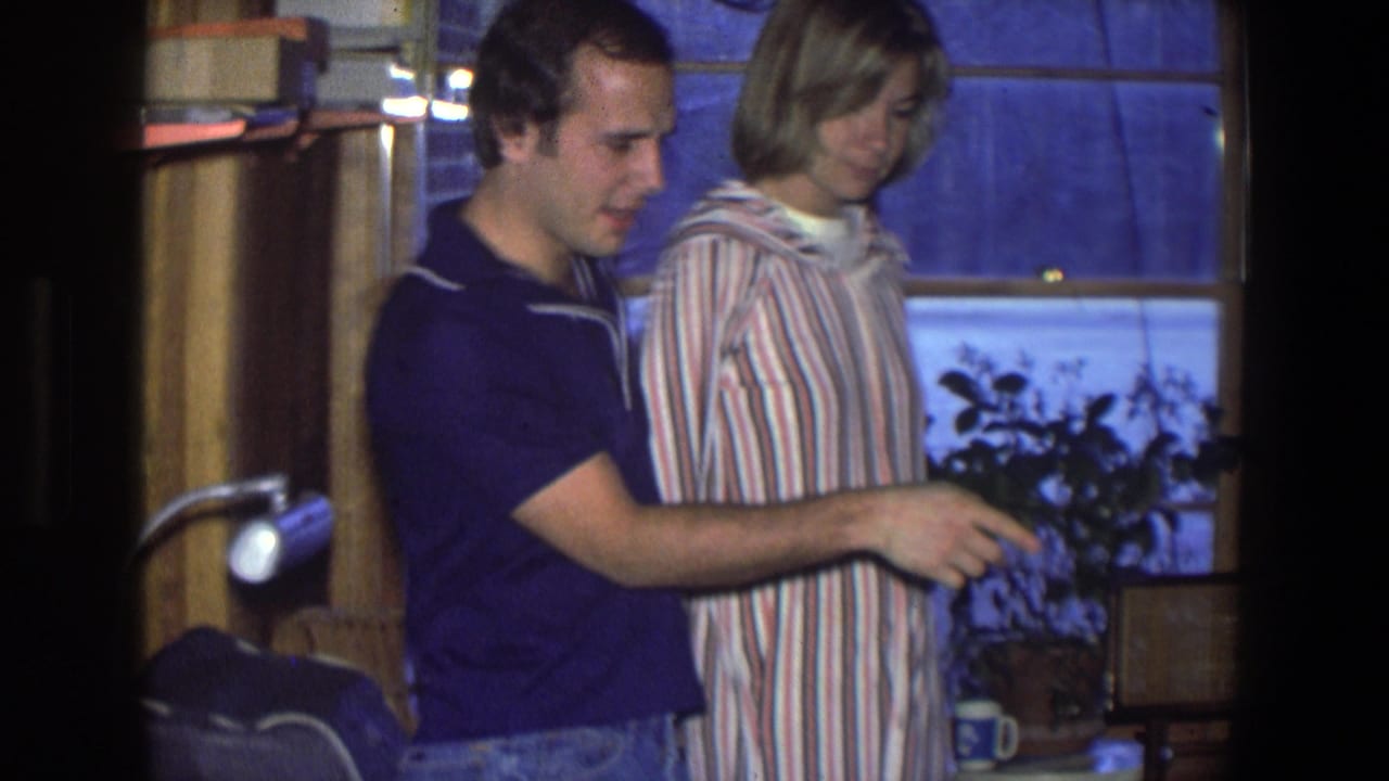 In a 1971 Saint Paul home interior, a couple stands close together near a snowy window and potted plant.