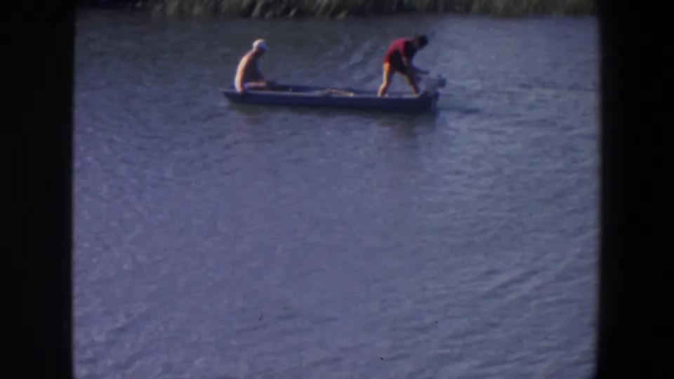 1971 Saint Paul 8mm frame with a small motorboat on open water, a seated man at the bow, and another man standing at the stern.