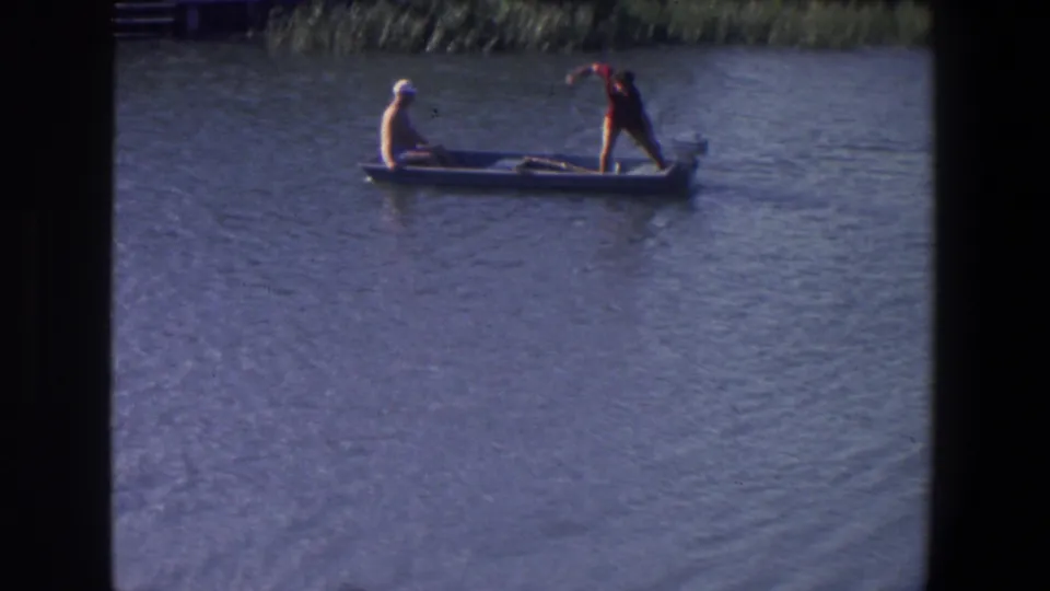Saint Paul, Minnesota 1971 home-movie frame showing a man in a red shirt standing in a small boat and another seated near the bow.