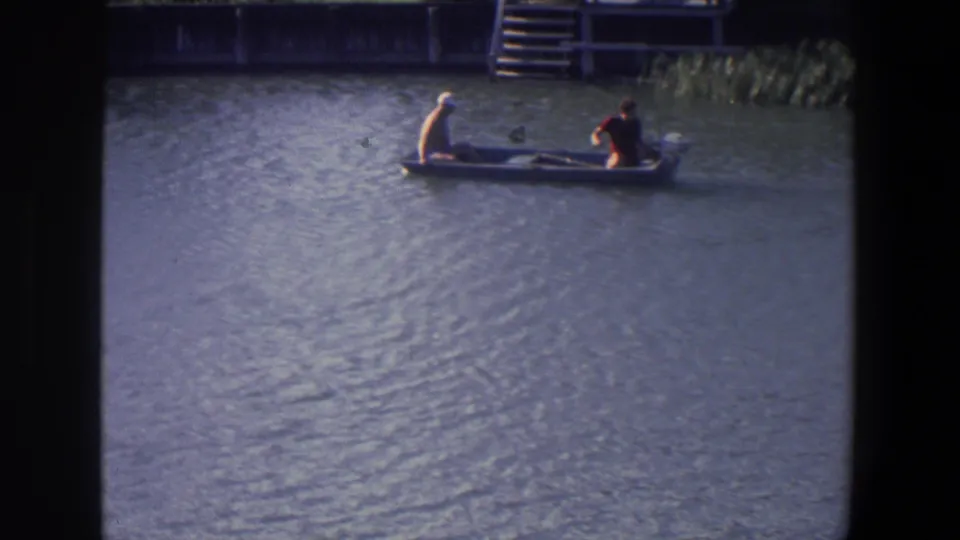 The 1971 Saint Paul home movie shows the boat continuing across the water, with reeds, steps, and a docklike structure behind it.