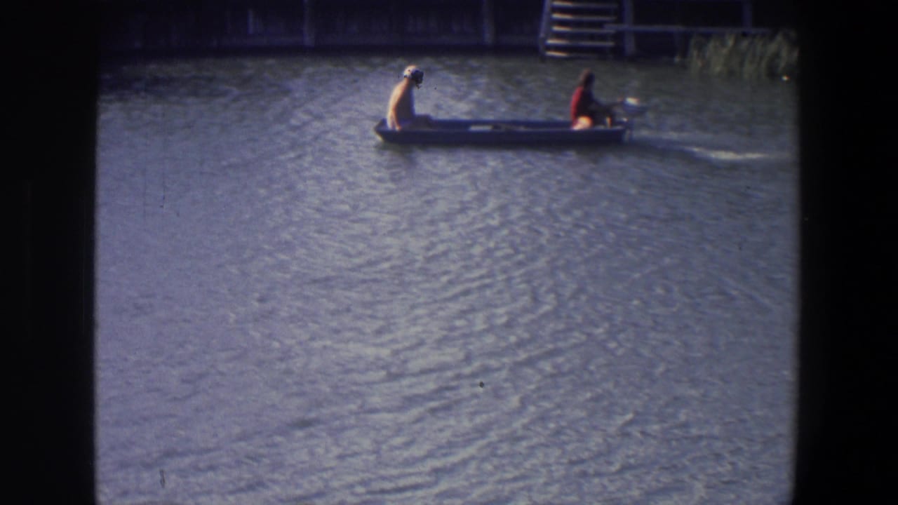 Two people ride a small motorboat across rippled lake water near a dock.