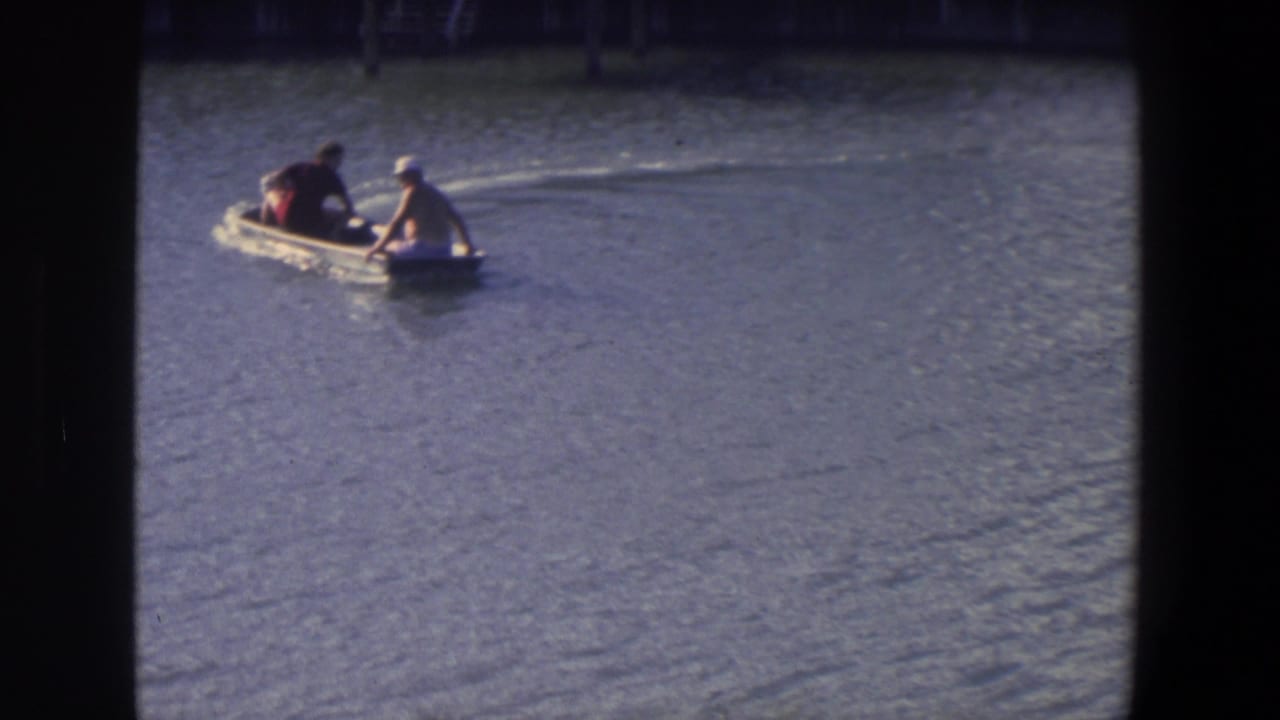 Two people ride in a small motorboat across rippled water.
