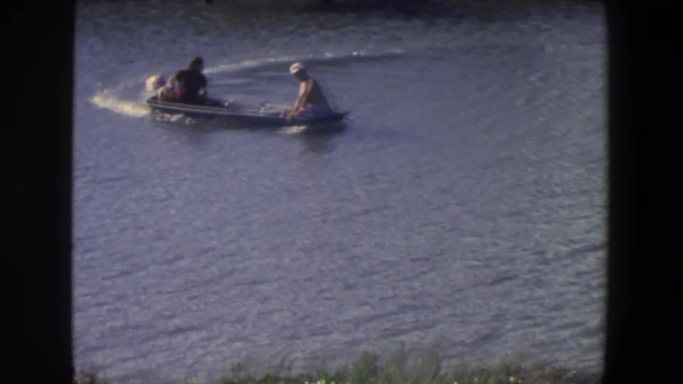 A small motorboat carrying two people arcs across the water, leaving a light wake in Saint Paul, Minnesota.