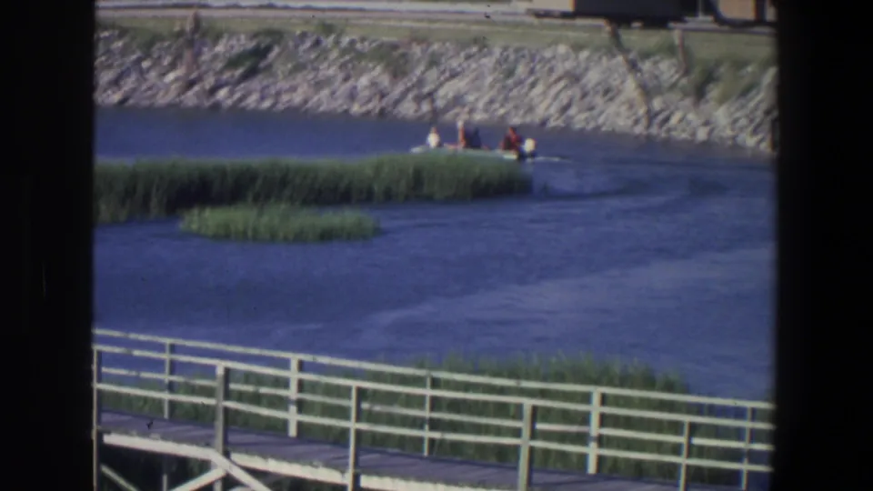 1971 Saint Paul river scene showing a small passenger boat near reeds, viewed over a white railing on 8mm film.