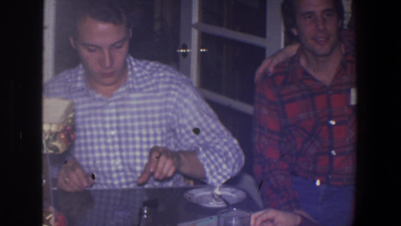 Two young men at a table, one in checkered shirt and one in red plaid.