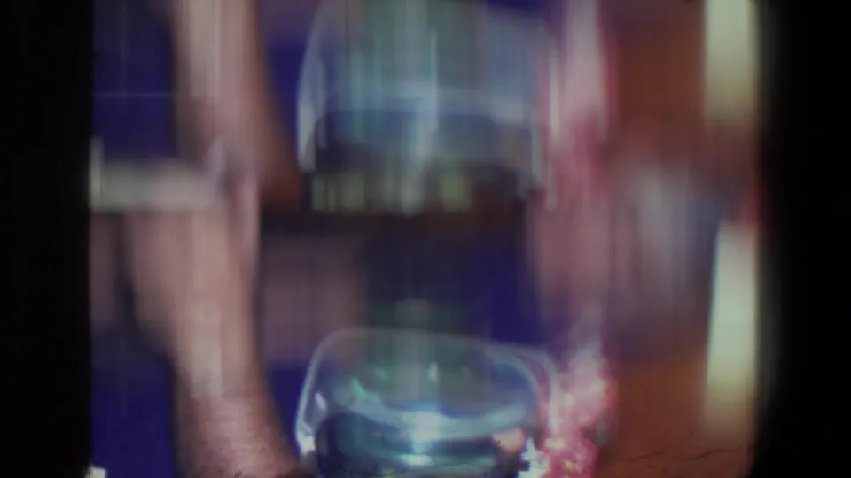Motion-blurred 8mm frame from the Saint Paul interior, with a seated arm, tableware, and strong handheld movement.