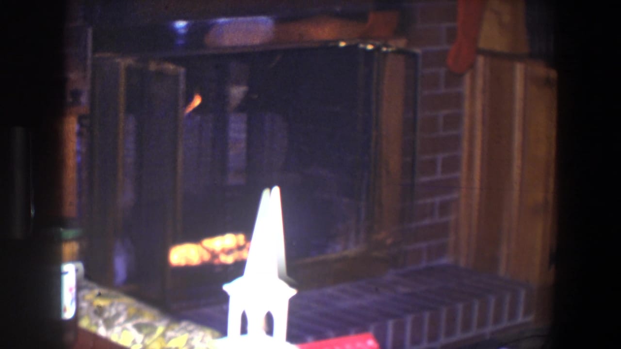 Brick fireplace with fire, hearth, model church, and wood-paneled room details.