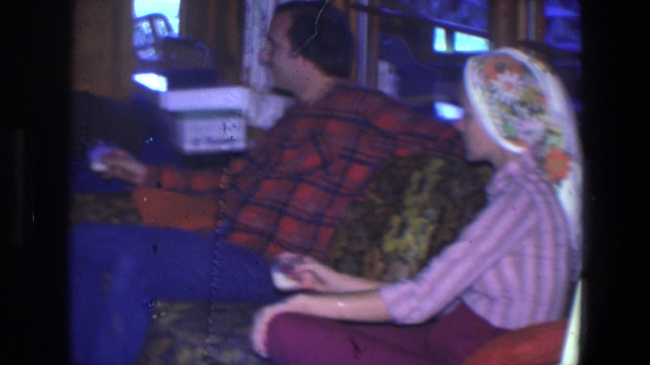 Man and woman sit side by side on a sofa with drinks in hand.