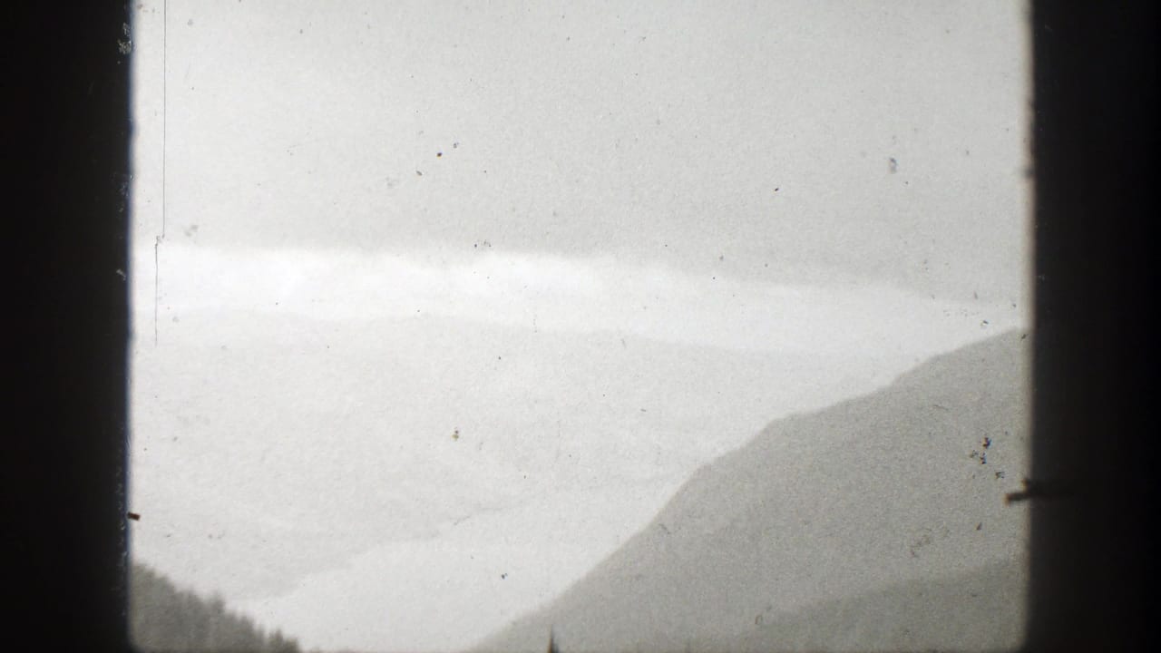 Misty California mountain landscape from 1938 home-movie footage, partly obscured by dark vertical frame edges.