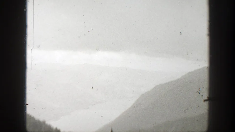 Misty California mountain landscape from 1938 home-movie footage, partly obscured by dark vertical frame edges.