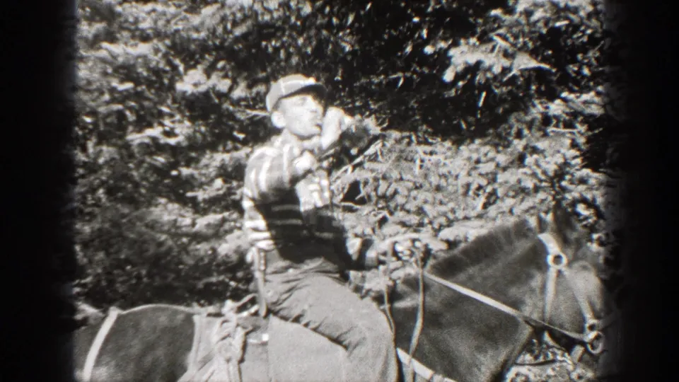 Adult man in a cap and striped shirt rides a saddled horse in a California pine forest, 1938 home-movie footage.