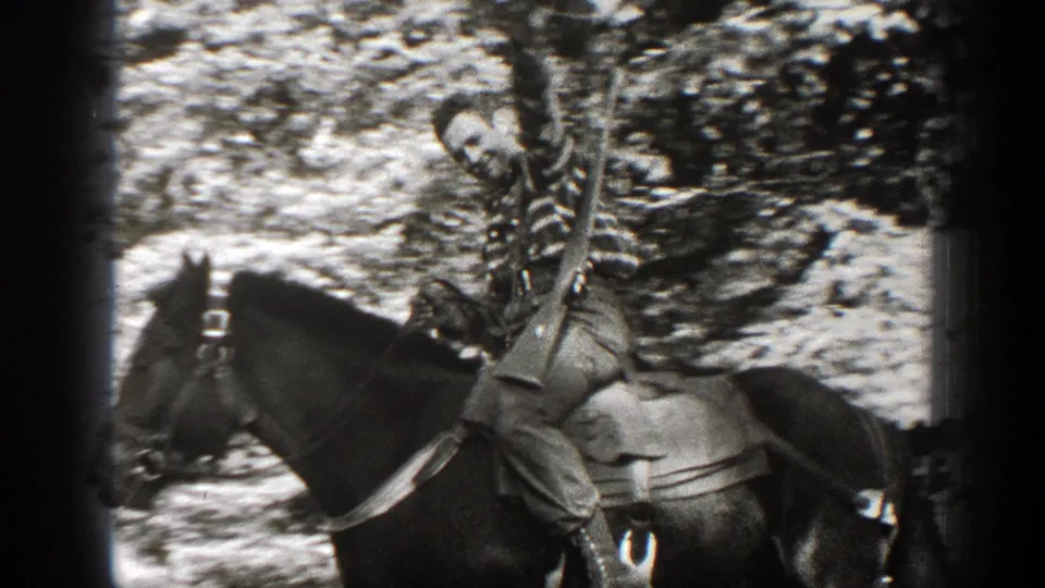 1938 California 8mm frame showing a cowboy-dressed rider on horseback in a wooded outdoor setting.