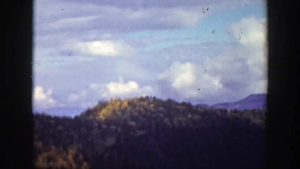 1938 California home-movie view of a wooded ridge and distant hills under a clouded sky.