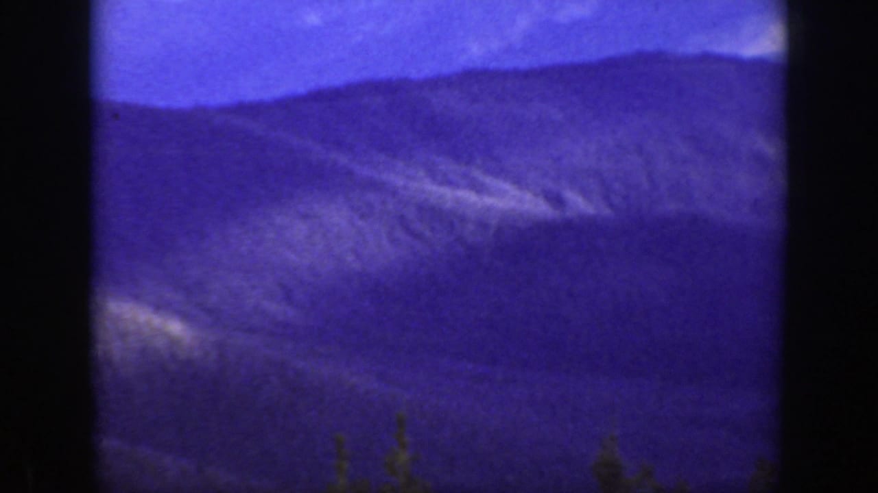 Blue-purple mountain ridges under sky with dark film-frame borders.