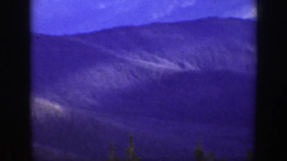 1938 California 8mm frame showing layered mountain ridges beneath a blue-purple sky, with dark scan borders at the sides.