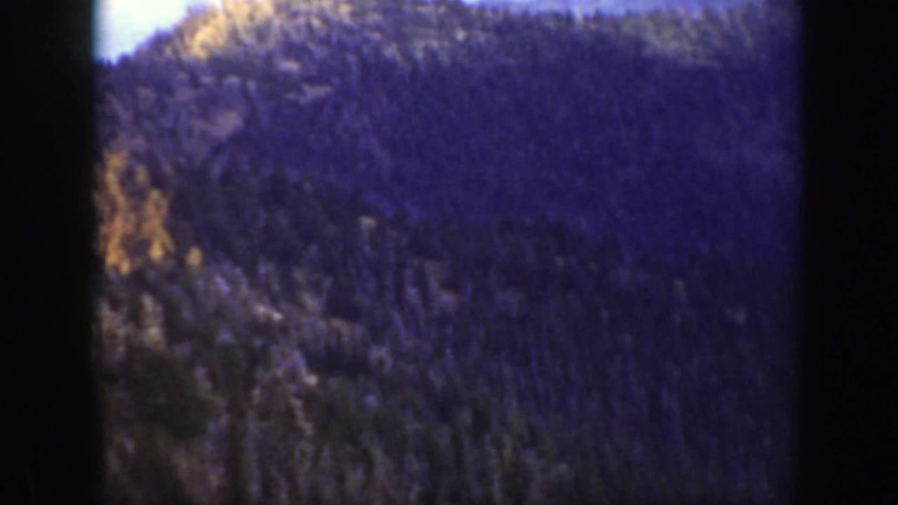 Forested mountain ridge and dark film frame edges.