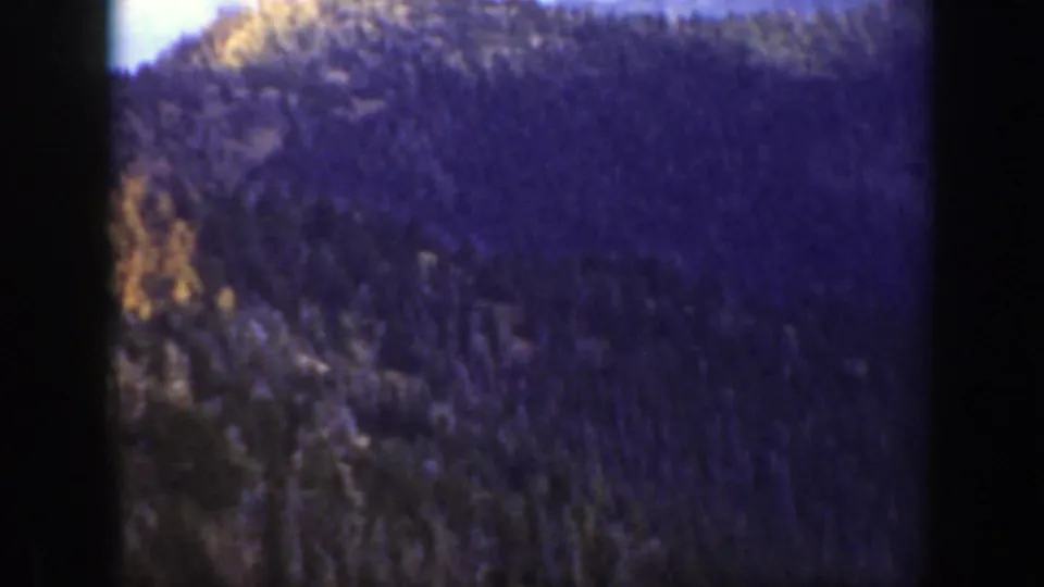 Soft 8mm view of a forested California mountain ridge, with heavy shadowing and frame edges visible.
