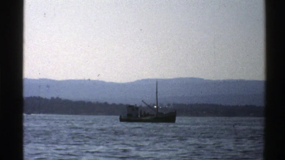 A small fishing boat moves across Norwegian coastal water in a soft, grainy 1976 8mm home-movie frame.