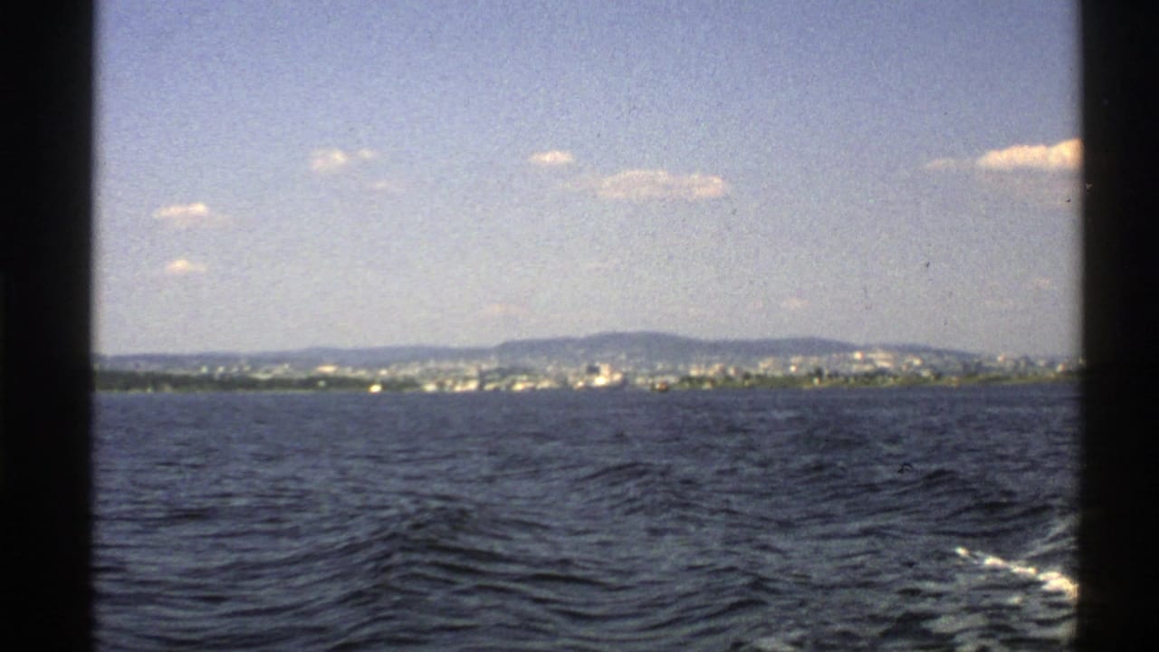 Open sea with a distant shoreline and hills under a bright sky.