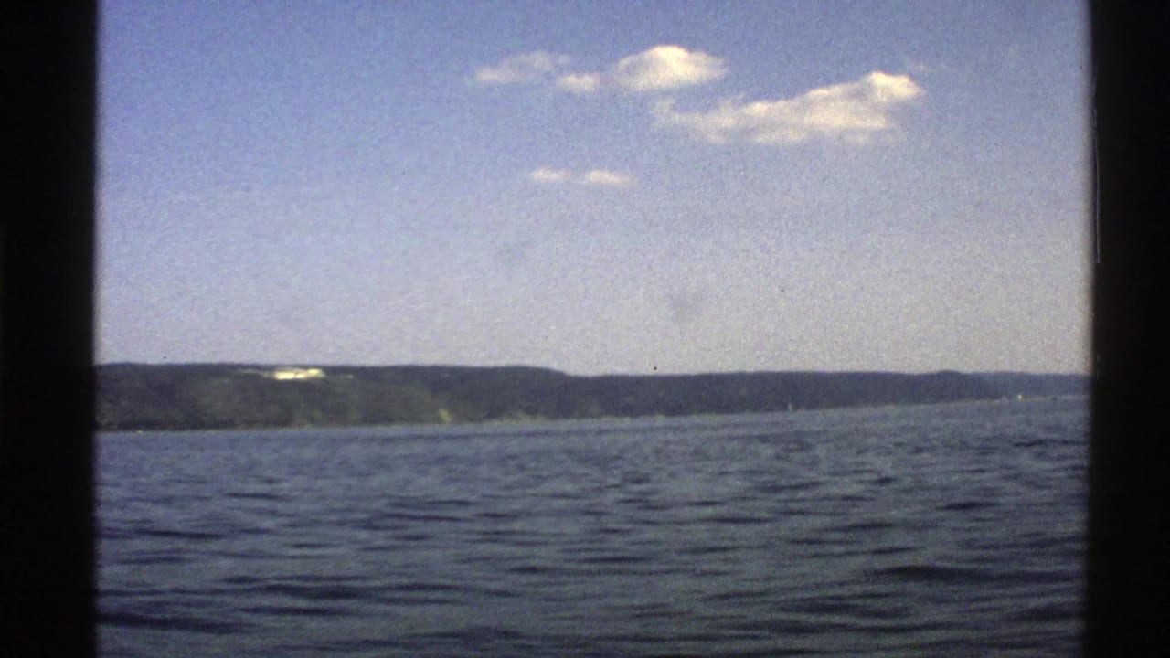 Open water under a pale sky with a distant low shoreline and clouds.