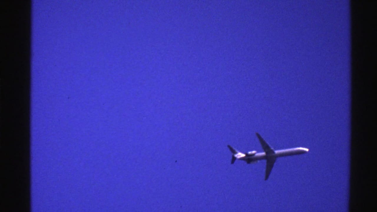 Jetliner farther right in a clear blue sky with a dark vertical film border.