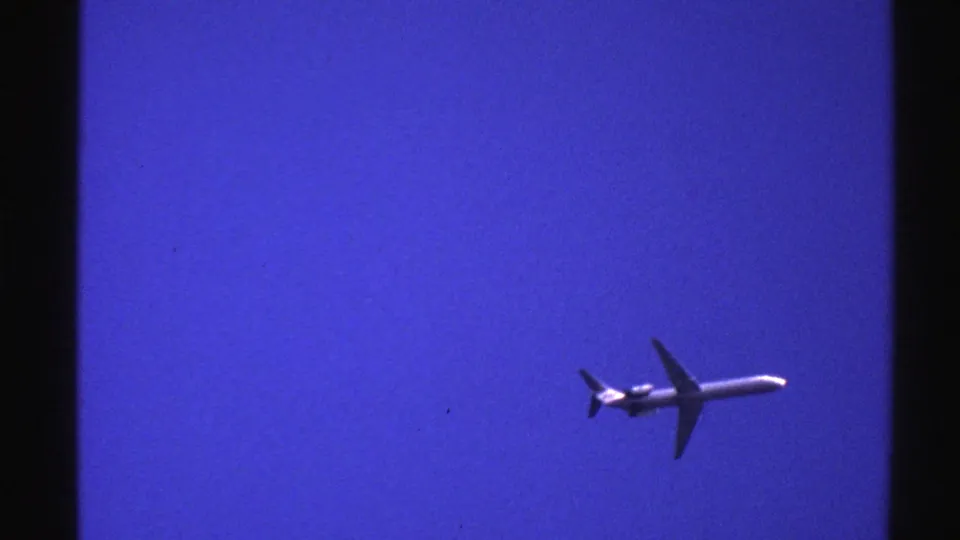 The aircraft appears to continue across the blue sky in this 1976 Norway 8mm home-movie frame, with no ground detail visible.