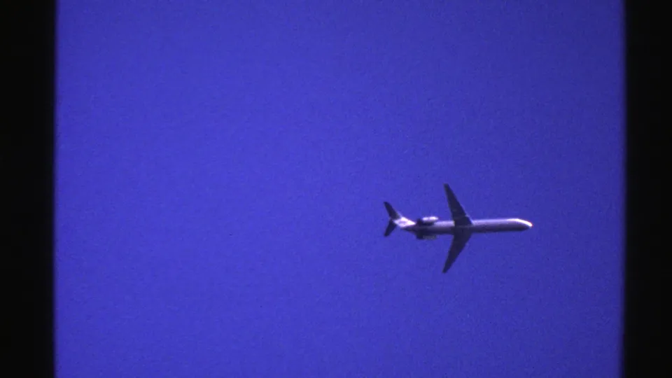 A commercial jetliner is framed low against a saturated blue sky in this 1976 Norway 8mm aviation shot.